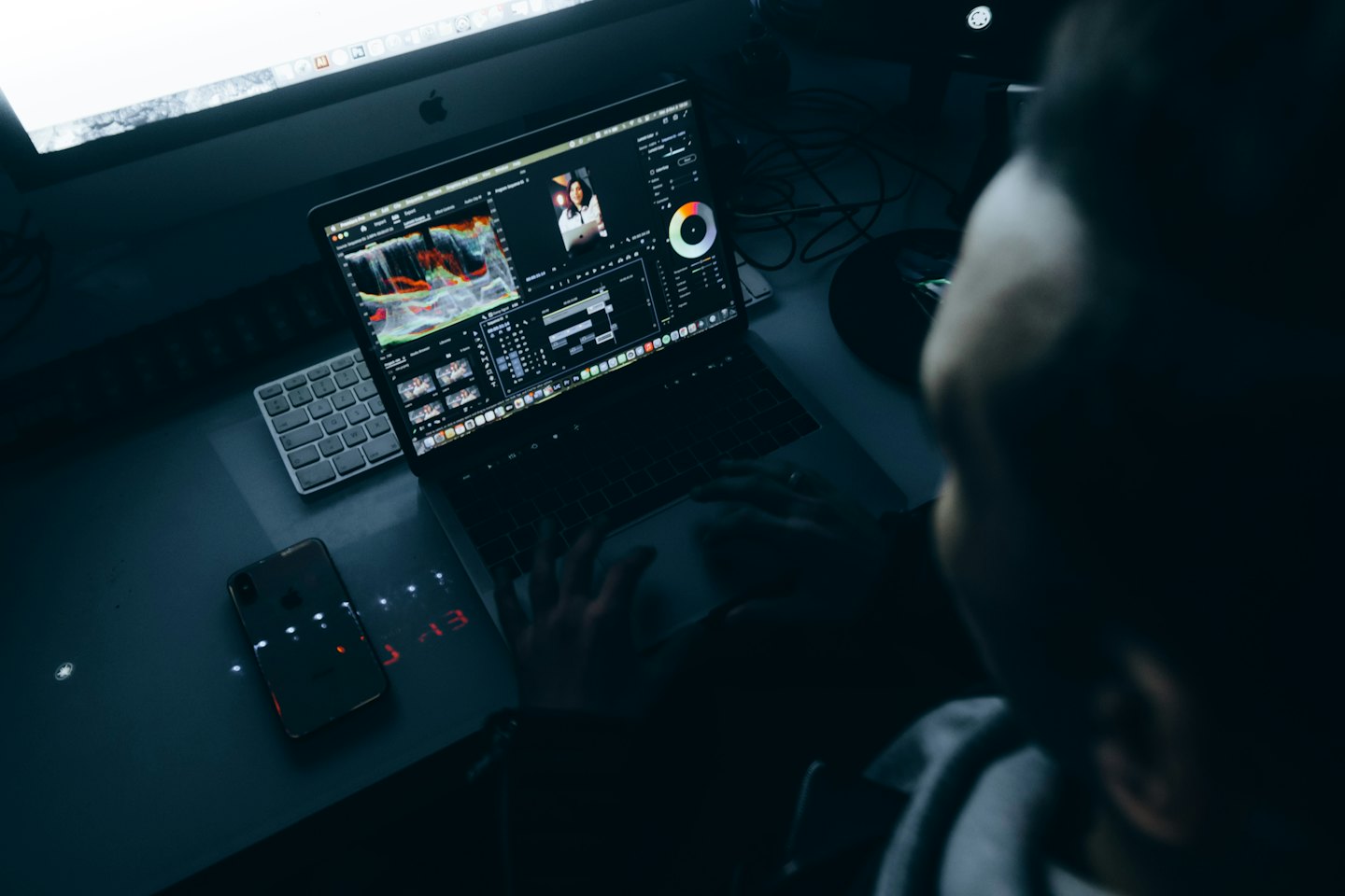 Person editing video on a laptop at a desk.